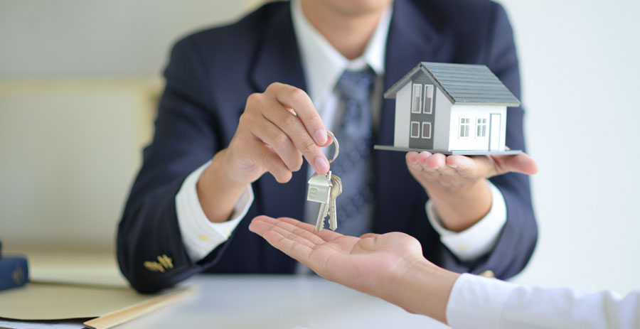 Vermittlung einer Immobilie - Mann übergibt Schlüssel und Immobilie